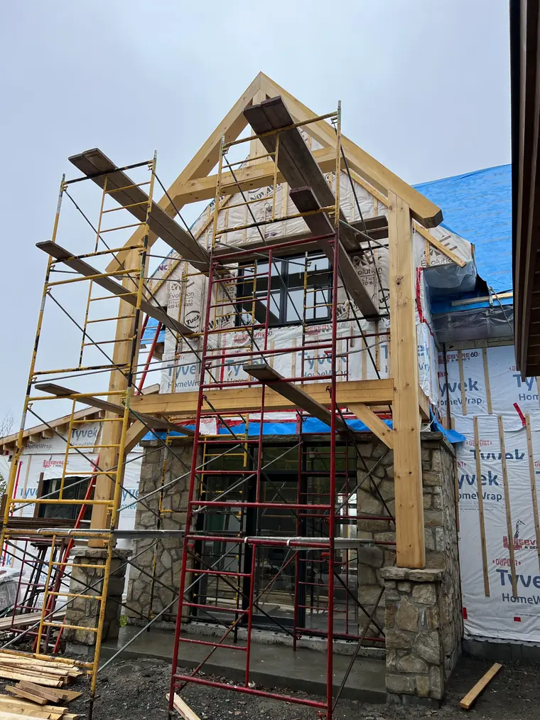 Charpente en bois massif et colonnes de pierre en cours de construction
